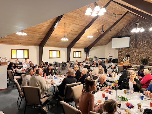 Congregation attending an event at the church, sitting at round tables enjoying good conversation and food and beverages